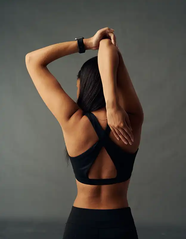 Frau von hinten bei physiotherapeutischen Übung für die rechte Schulter.